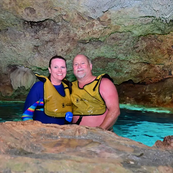 Couple smiling in a cave cenote, relaxing after an exciting snorkeling experience in Riviera Maya