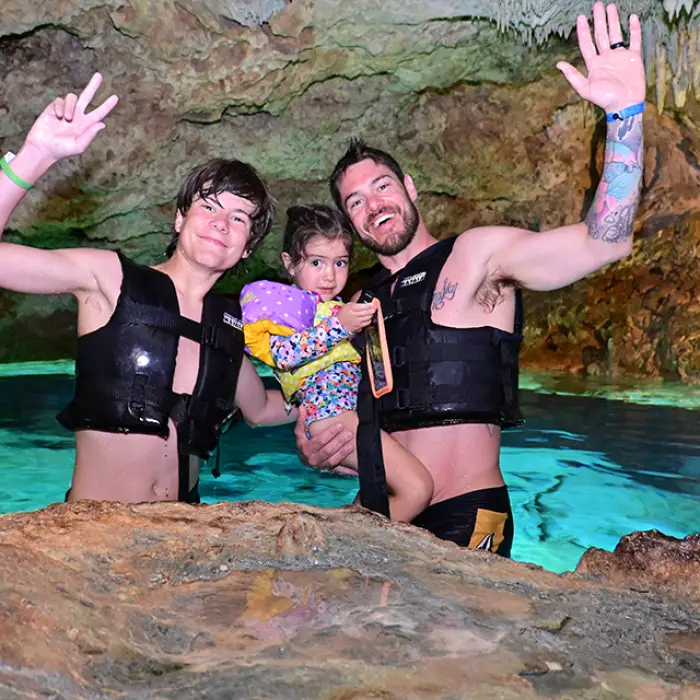Happy family posing inside a cenote cave, enjoying their experience on the Adventure Snorkeling Tour