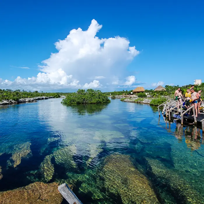 Visitors preparing to snorkel from a wooden platform overlooking a clear lagoon with stunning reflections