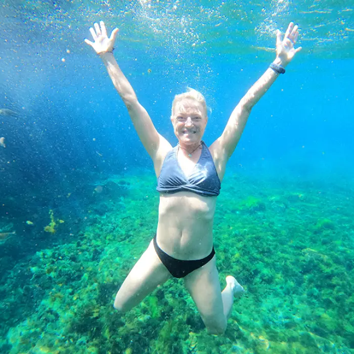 Woman joyfully posing underwater while snorkeling in vibrant reef waters on the Riviera Maya tour
