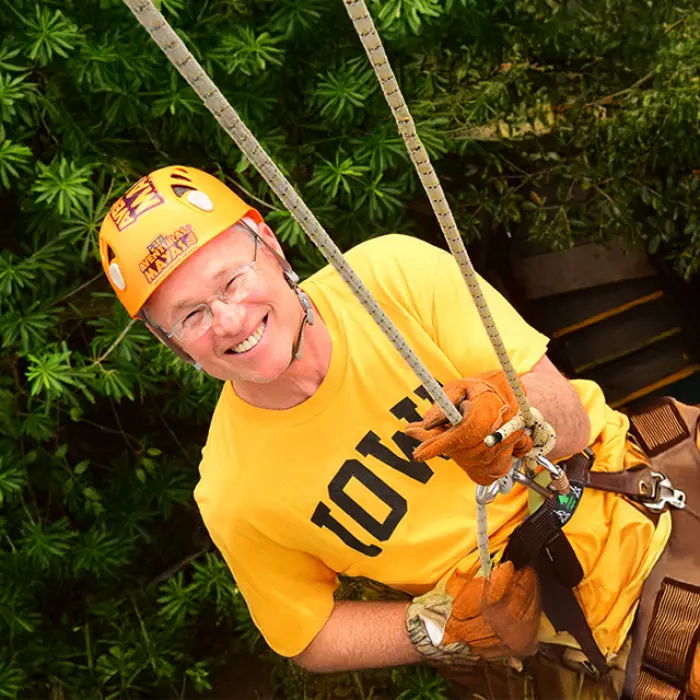 Man smiling while descending on a rappel during the Mayan Adventure Tour experience in the jungle