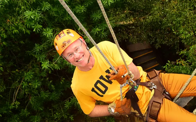 Man smiling while descending on a rappel during the Mayan Adventure Tour experience in the jungle