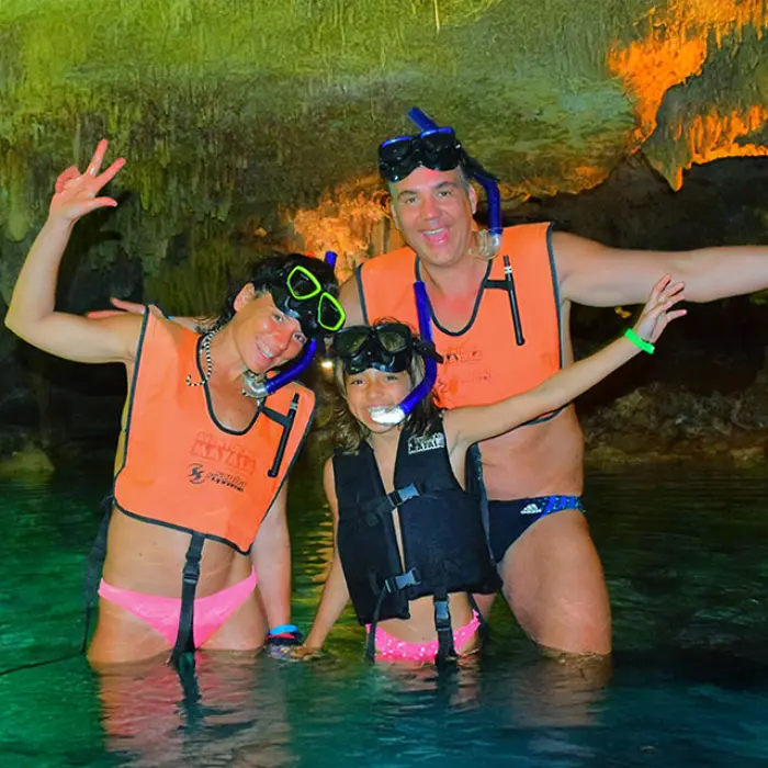 Family with kids snorkeling inside a mystical cenote cave in the Riviera Maya on the Mayan Adventure Tour