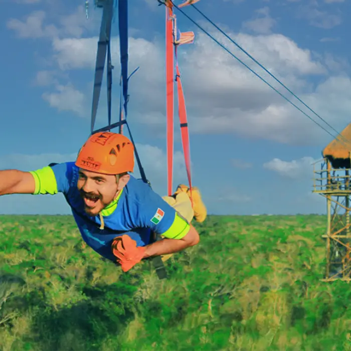 Man flying in Superman pose on a zipline above the jungle canopy, part of the adventure snorkeling tour