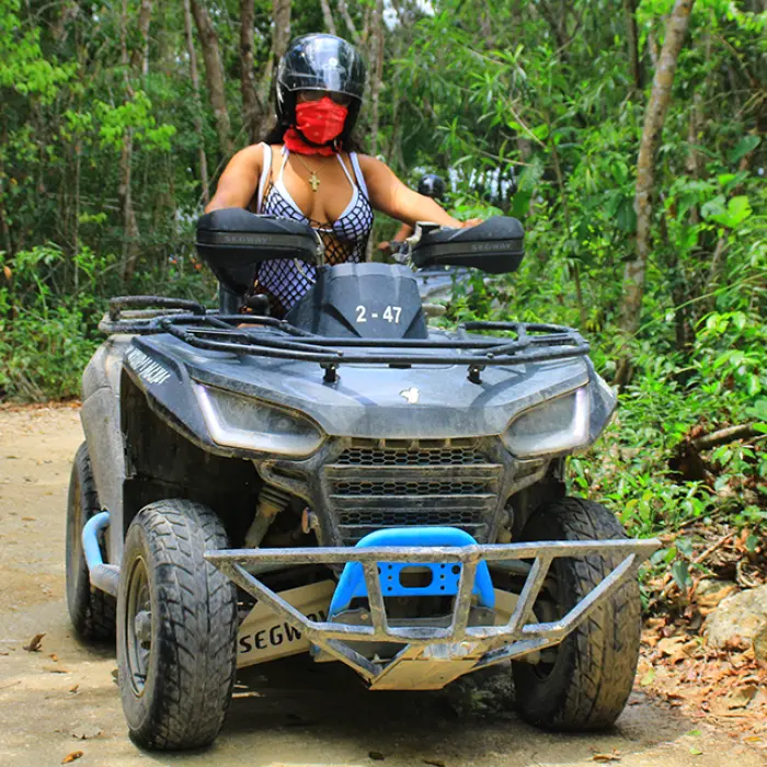 Two friends riding an ATV through the jungle trails on an adventure tour in Riviera Maya