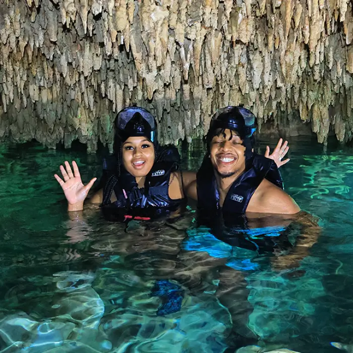 Couple enjoying the cool, clear waters of a hidden cenote cave