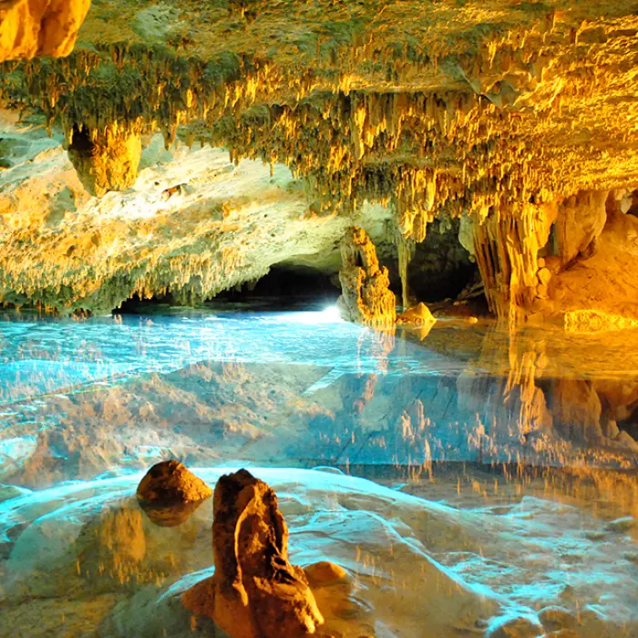 Beautiful underground cenote with crystal-clear water and golden cave walls