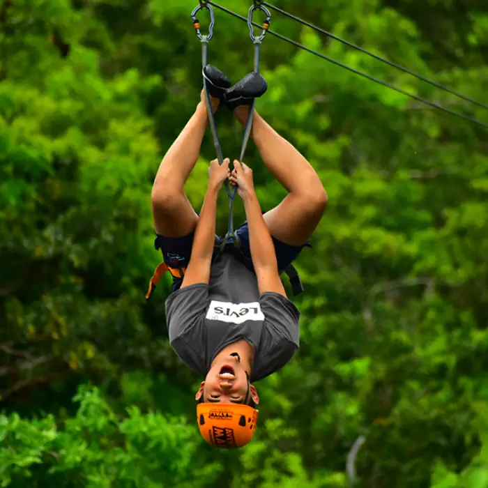 Adventurer ziplining upside down for a thrill ride in the jungle canopy