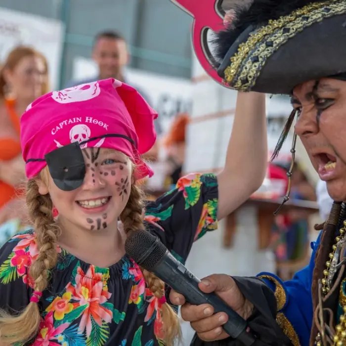 Captain Hook Cancun, a pirate with a microphone, entertains a young girl dressed as a pirate