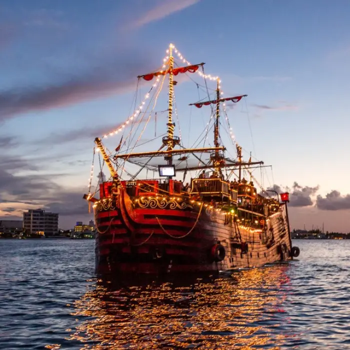 Captain Hook Cancun illuminated pirate ship sailing at dusk