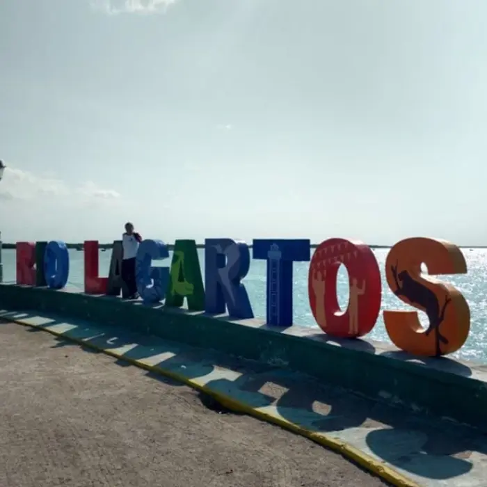 The iconic and colorful Rio Lagartos town sign standing proudly on the malecón, with the beautiful blue water in the background.