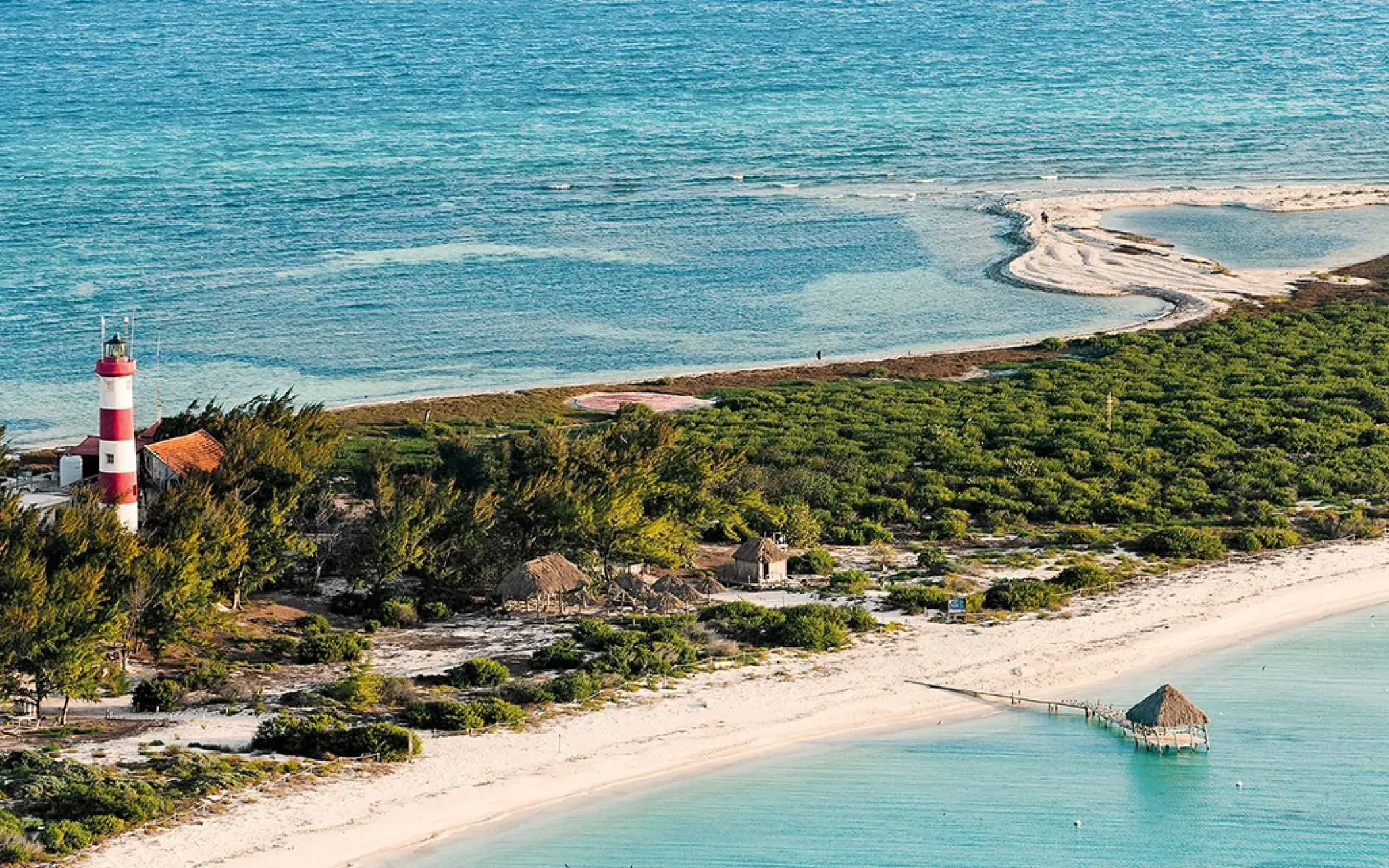 A beautiful aerial view of the Rio Lagartos coastline, featuring a classic red-and-white striped lighthouse, sandy beaches, and turquoise water.