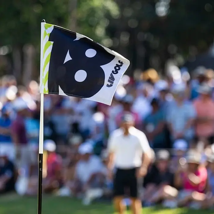 A close-up of the 18th hole flag with a large gallery of spectators watching a tournament at El Camaleón golf course in Mayakoba.