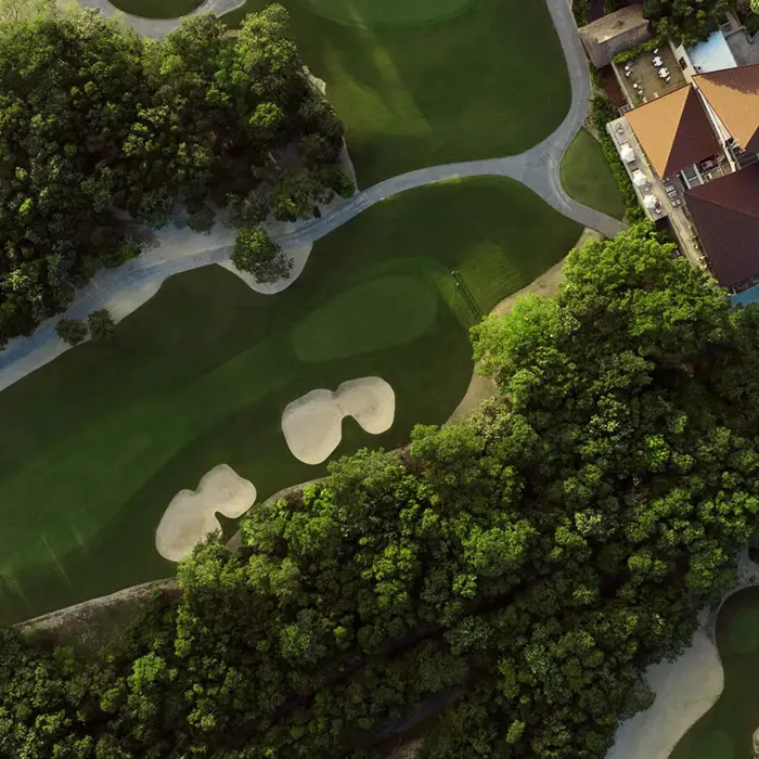 An aerial view looking straight down at the lush jungle fairways, sand traps, and luxury clubhouse at El Camaleón Golf Course in Mayakoba.