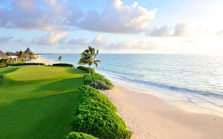 A beautiful oceanfront green running right alongside the white sand beach and turquoise Caribbean Sea at Mayakoba resort.