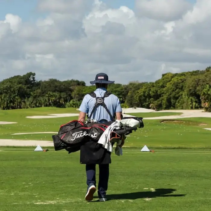 A golfer carries his bag towards the premium outdoor practice facilities and driving range at Gran Coyote.
