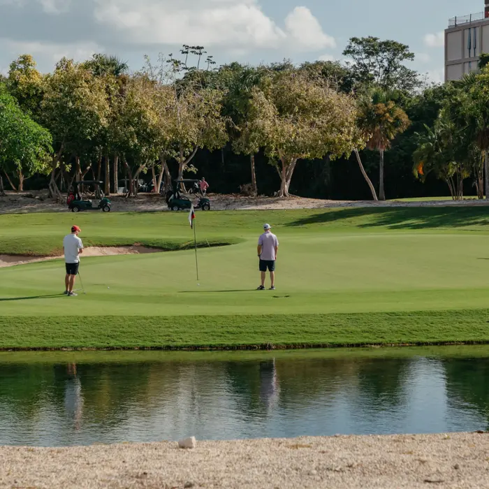 Golfers enjoy a relaxed round, putting on a smooth green right behind a water hazard at Gran Coyote Golf Club.