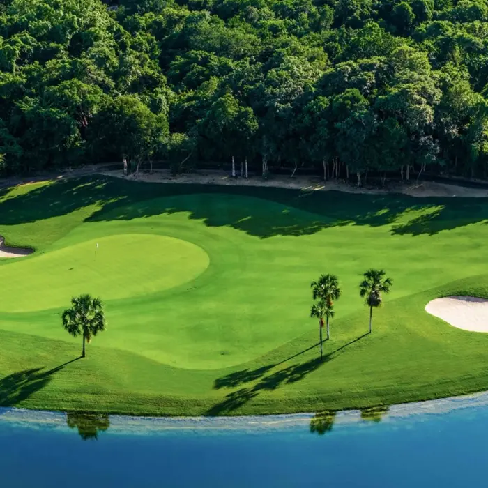 A stunning green surrounded by a bright blue lake and deep sand bunkers at the Nick Price-designed Gran Coyote in Riviera Maya.