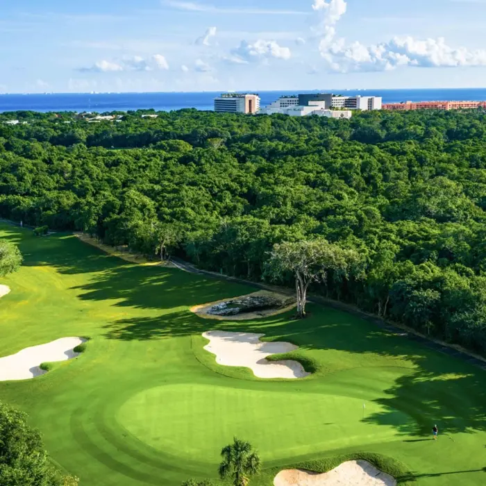 An immaculate green protected by sand bunkers, completely surrounded by dense native jungle at Gran Coyote Golf Club.