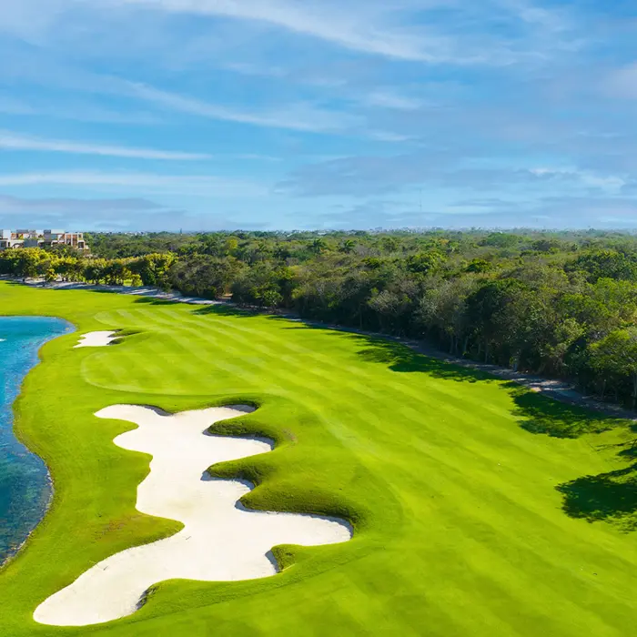 A beautifully manicured wide fairway curving alongside a pristine blue lake at the Nick Price-designed Gran Coyote course.