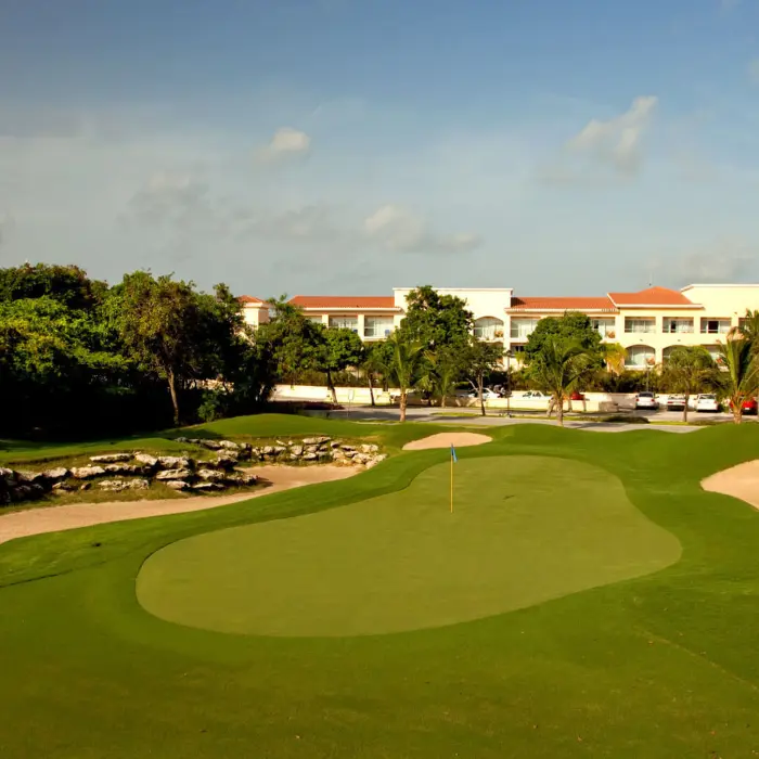 A wide view of the championship golf course with pristine bunkers and the Hard Rock resort in the background.