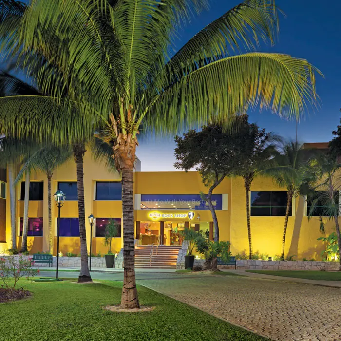 The illuminated exterior of the Hard Rock Golf Club clubhouse and rock shop at dusk in the Riviera Maya.