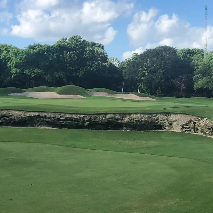A challenging golf green surrounded by natural rock formations and lush jungle at Hard Rock Riviera Maya.