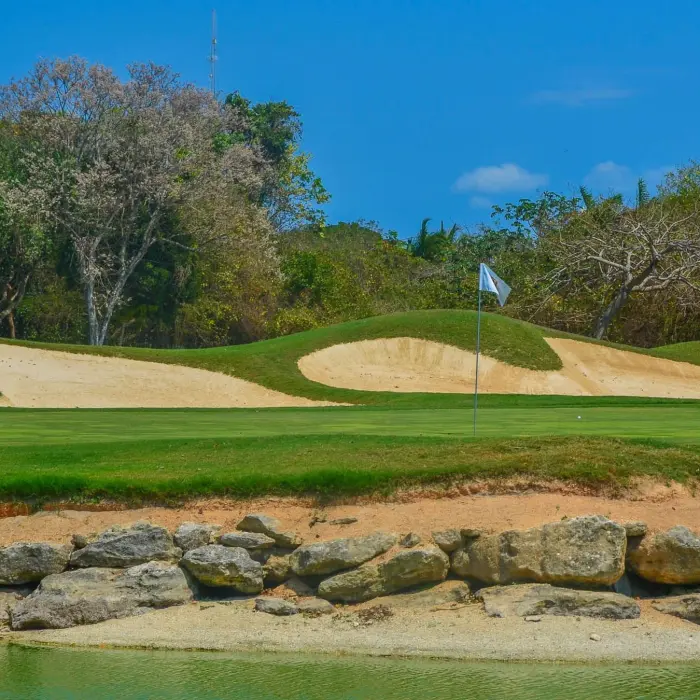 A challenging golf green bordered by natural stone and a large sand bunker at the Hard Rock Golf Club.