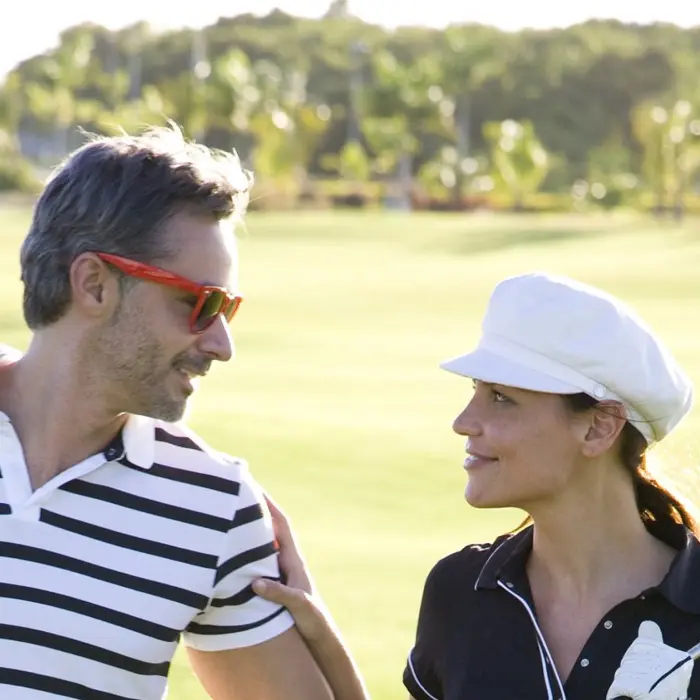 A happy couple smiles at each other while enjoying a relaxed and fun round of golf together at Hard Rock Riviera Maya.