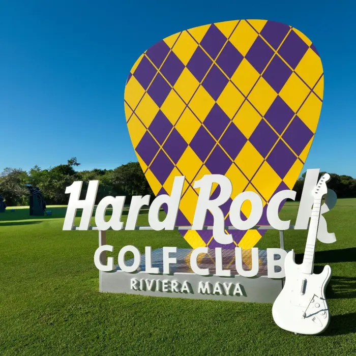 The iconic guitar pick sign and white guitar at the entrance of the Hard Rock Golf Club Riviera Maya practice facility.