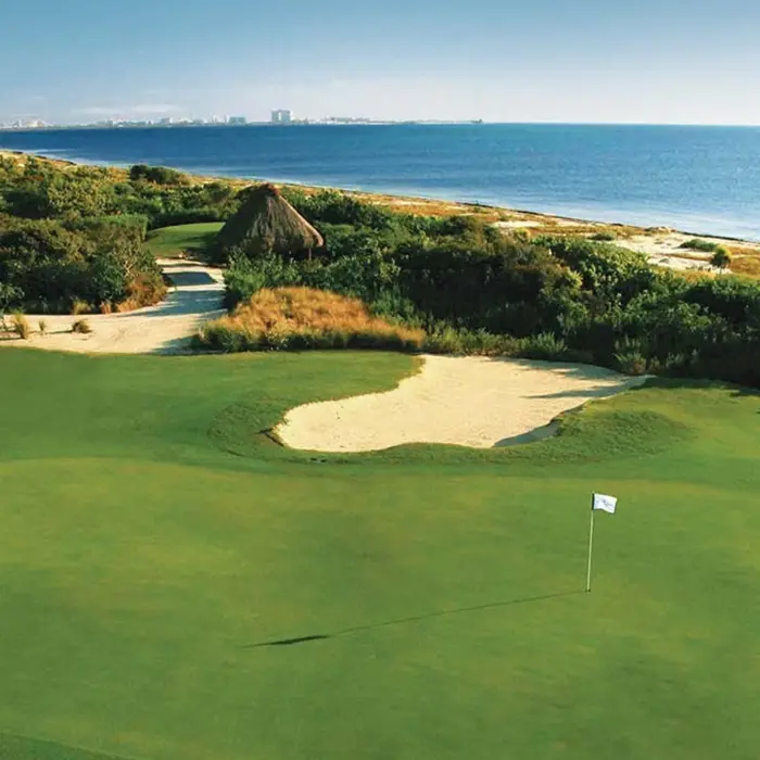 A breathtaking view of a golf green situated near the beautiful coastline and ocean waters in the Riviera Maya.