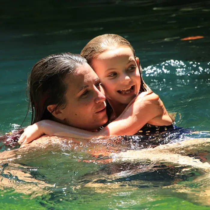 Cenote family time Playa del Carmen: Mother and daughter embracing in the clear, refreshing water of a cenote