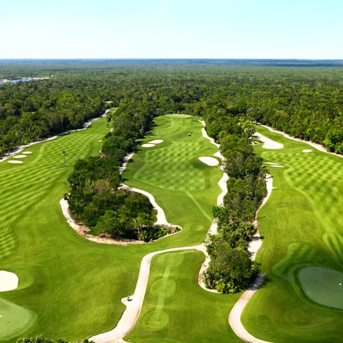 An expansive aerial view showing the rolling fairways of the P.B. Dye championship golf course carved into the dense jungle