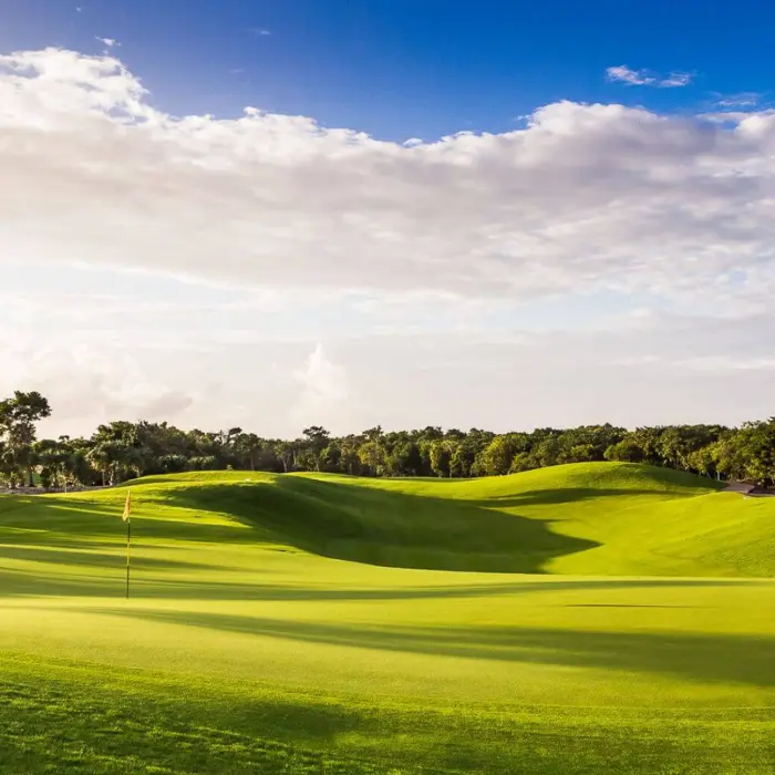Stunning golden hour lighting casts dramatic shadows over the rolling fairways of the P.B. Dye-designed Iberostar golf course