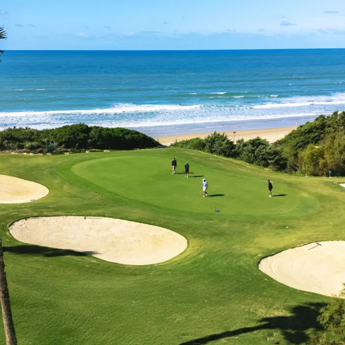 Golfers putt on a beautiful oceanfront green bordered by sand bunkers and stunning views of the Caribbean Sea.
