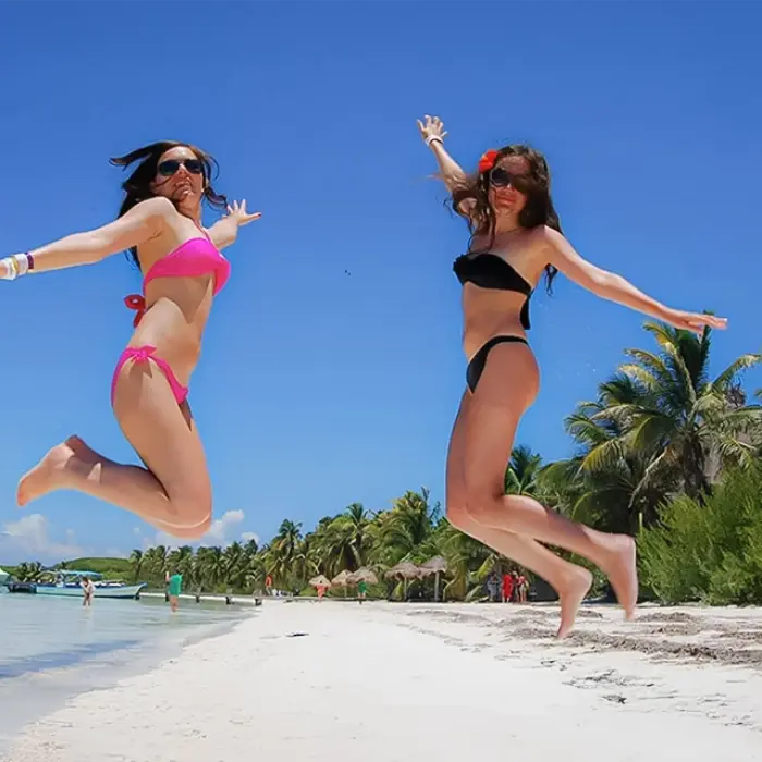 Friends jumping on the white sand of Isla Contoy during the Paradise Islands experience