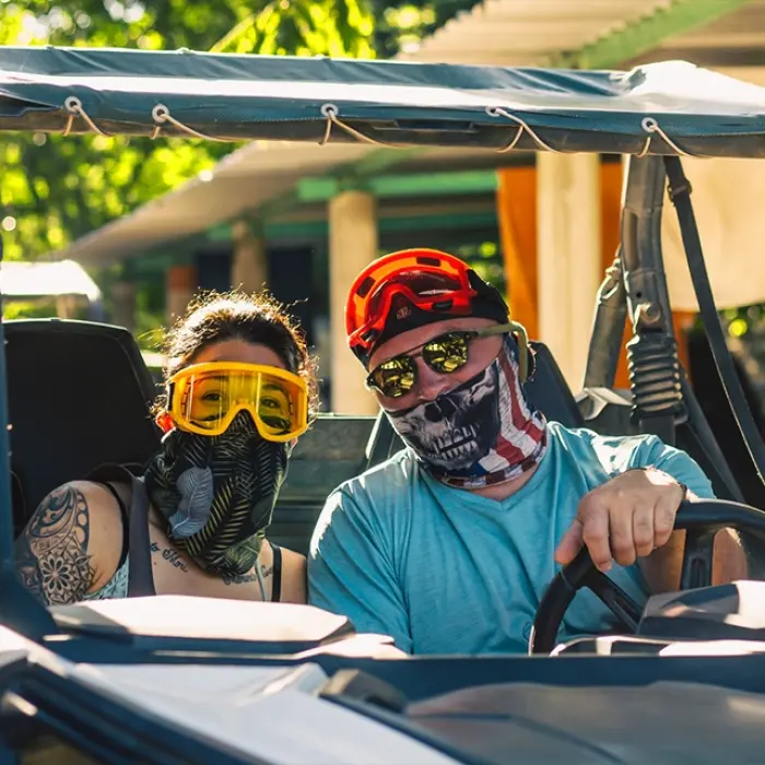 Couple smiling in a buggy, ready for an adventurous off-road ride through the jungle trails
