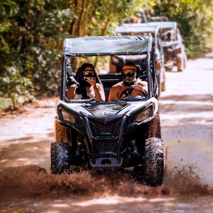 Couple in a buggy navigating through a muddy trail, enjoying an adventurous off-road ride