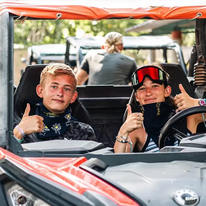 Two young boys smiling in a buggy, getting ready for an exciting off-road adventure in the jungle