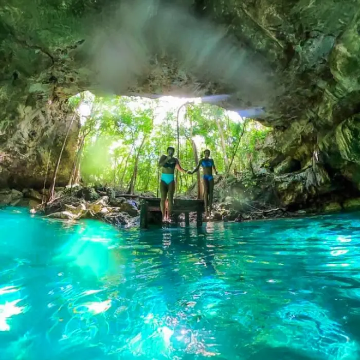 Two girls ready to swim in the clear water of a cenote, surrounded by natural beauty in the Riviera Maya