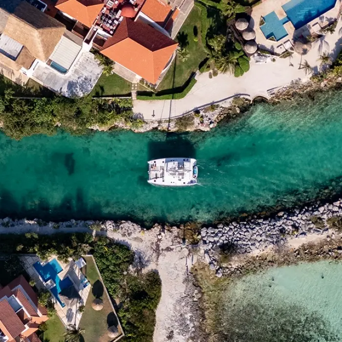 Aerial shot of a marina entrance with luxurious houses and yachts docked