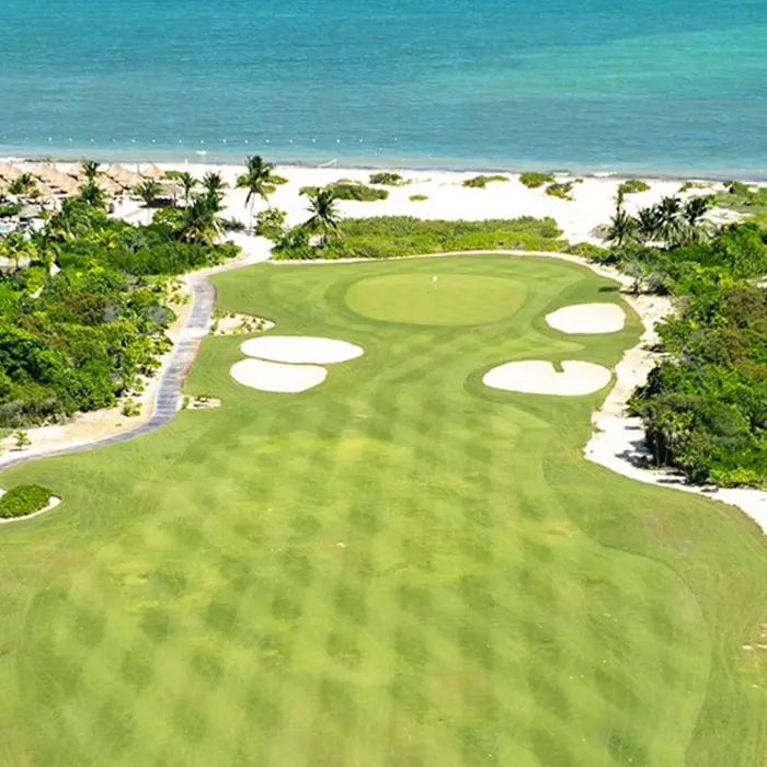Stunning aerial view of a championship golf green bordered by native tropical jungle and white sand beaches in Costa Mujeres