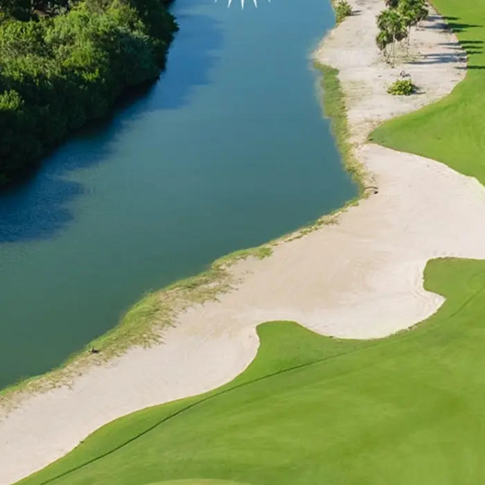 An expansive view of the Greg Norman-designed fairway at Playa Mujeres Golf Club, seamlessly integrated with natural water hazards and coastal wetlands