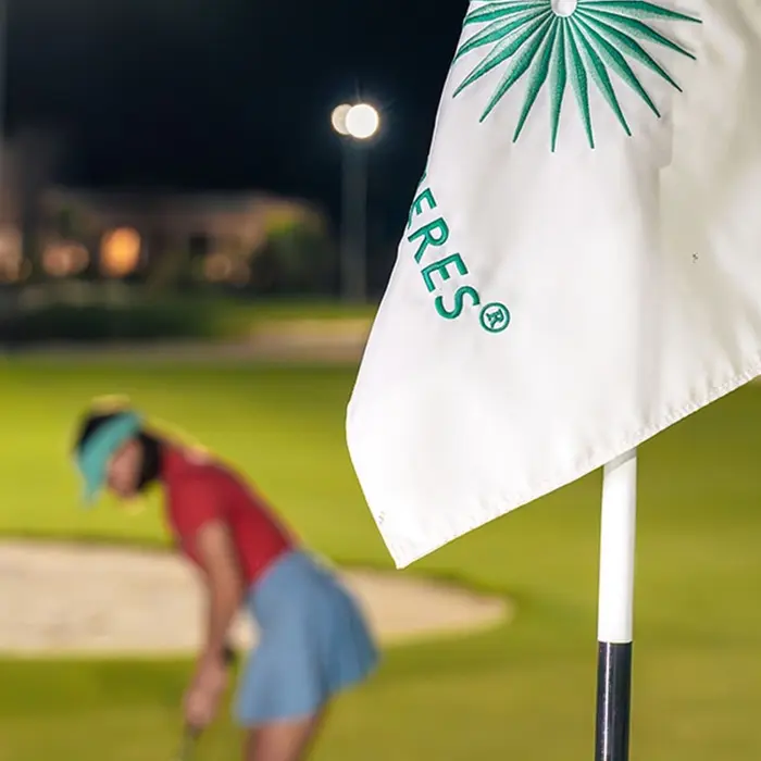 A group of friends enjoying a fun and relaxed round of golf, with one player taking a swing right next to their parked golf carts on the lush fairway