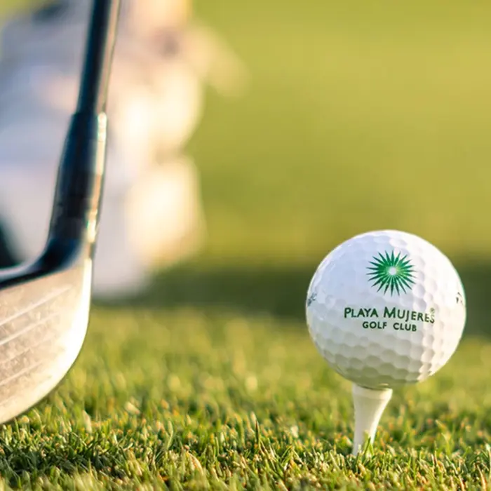 A close-up of a branded Playa Mujeres Golf Club ball on a tee ready for a drive on the pristine championship course