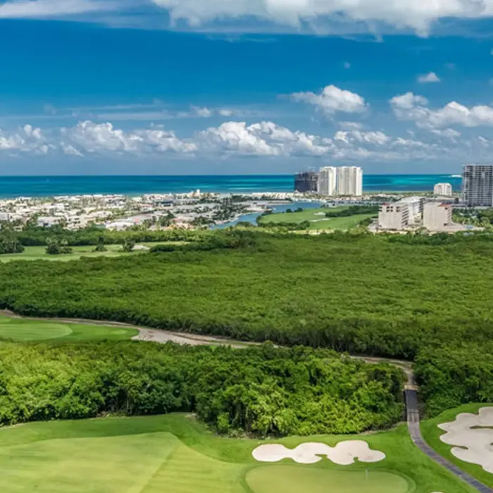 Expansive aerial view of the oceanfront championship course surrounded by mangroves and the Cancún skyline