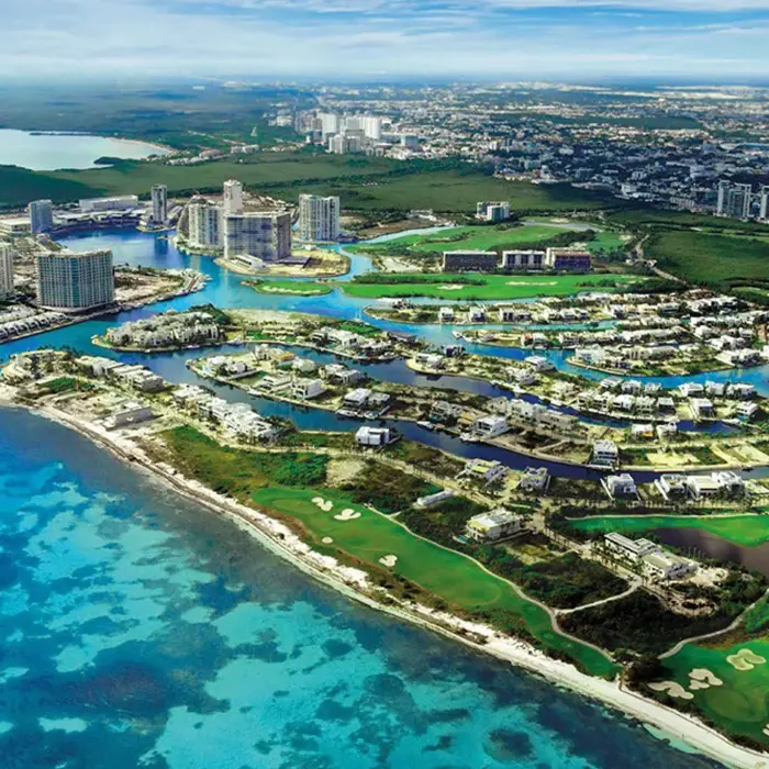 Aerial view of Puerto Cancún Golf Club showcasing the championship course, luxury marina district, and the beautiful Caribbean Sea.