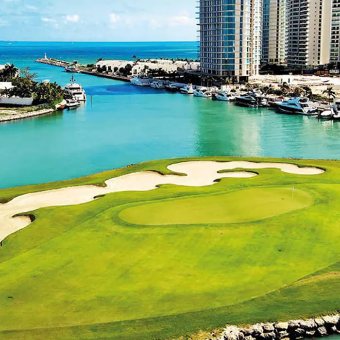 A pristine golf green and sand bunker located right on the edge of the turquoise waters at Puerto Cancún Golf Club.
