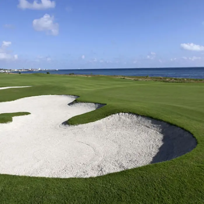 A massive uniquely shaped sand bunker protecting a smooth green overlooking the Caribbean Sea at Puerto Cancún.