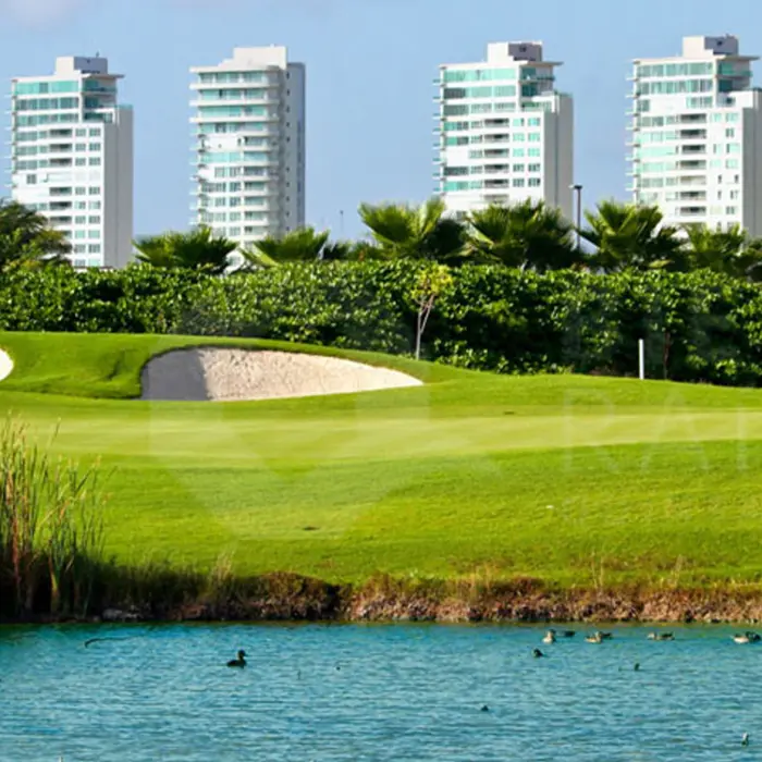 A beautiful golf hole featuring water hazards and sand bunkers with luxury high-rise buildings in the background.